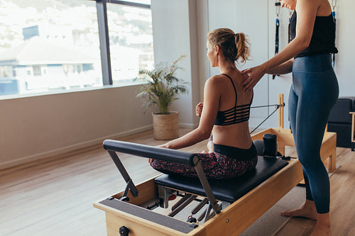 Woman doing pilates workout at the gym with her instructor