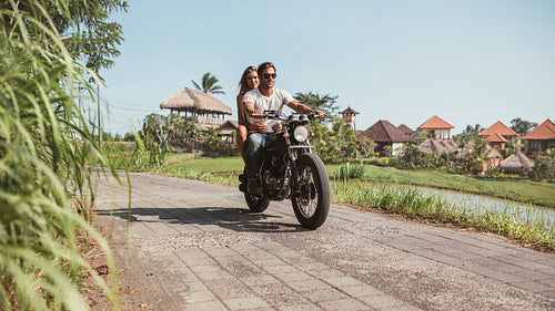 Young couple riding motorcycle on rural road