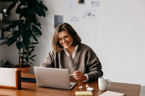 Woman working on laptop at home office desk in a cozy remote work setting