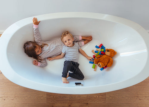 Little siblings playing inside a bathtub