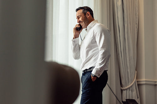 Businessman talking on phone from hotel room