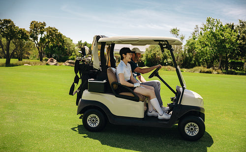 Golfers driving a golf cart on a well-maintained fairway at a golf resort