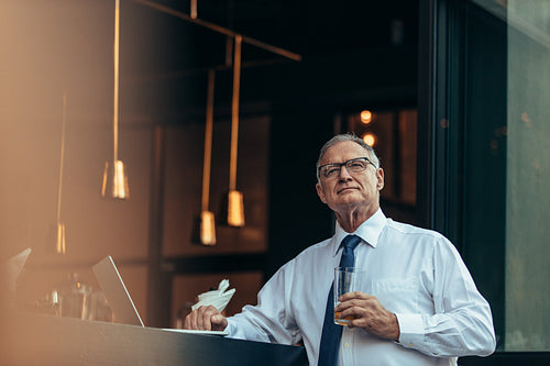 Thoughtful senior businessman having a beer at cafe
