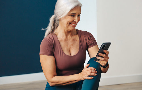 Yoga journey: Senior woman using a fitness app on her phone to plan her next yoga practice