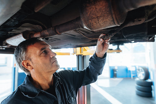 Mechanic checking electrical connections of a car in garage