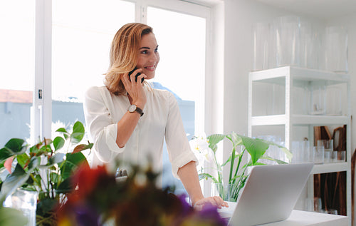 Florist using mobile phone at her flower shop