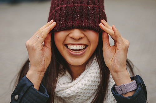 Portrait of a smiling woman with her face covered with a winter cap