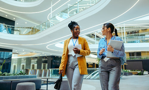 Professional female colleagues walking through a modern corporate office