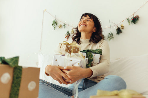 Woman sitting on bed with her christmas presents