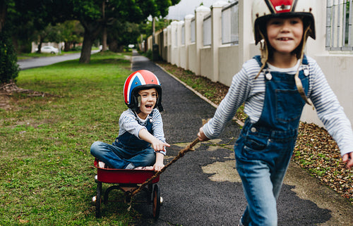 Identical twins playing outdoors with a trolley