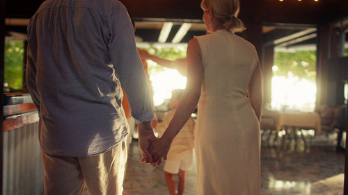 Happy family enjoys a wonderful evening together entering an elegant island resort restaurant