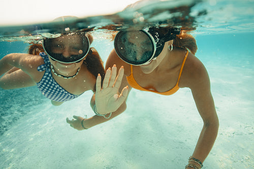 Sisters swimming together on vacation at an island, underwater shot of two girls enjoying summer fun