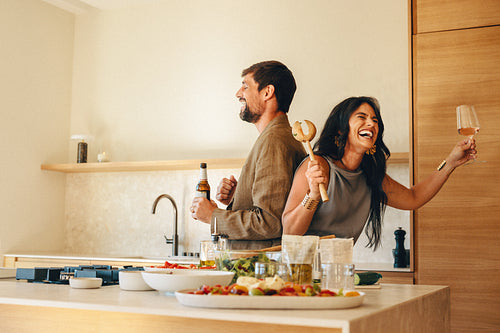 Couple enjoying a lively and joyful moment in a modern kitchen setting