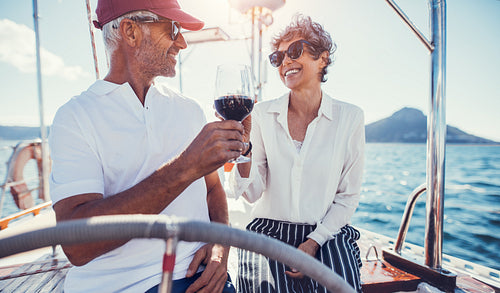 Happy senior couple enjoying wine on yacht