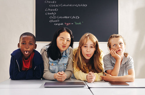 Diverse elementary school children making funny faces in a coding class