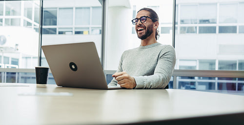 Happy businessman laughing cheerfully in a co-working office