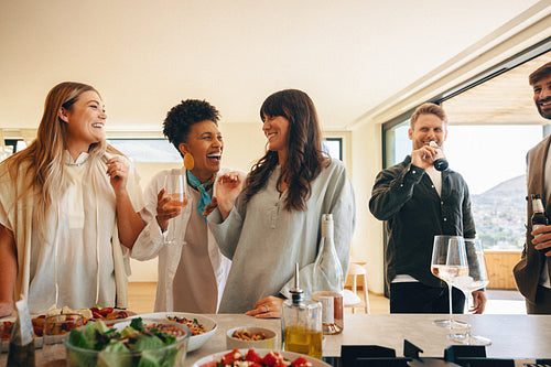 Friends enjoying drinks and food together at modern home with scenic views