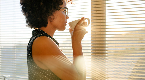 Businesswoman having coffee by office window
