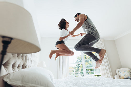 Couple jumping on bed