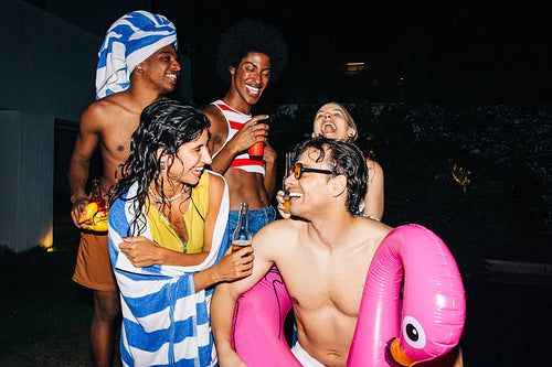Friends at night pool party with inflatable flamingo