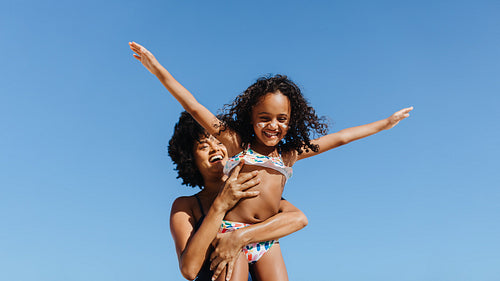 Mother and daughter enjoying a sunny day at the beach with sunscreen on