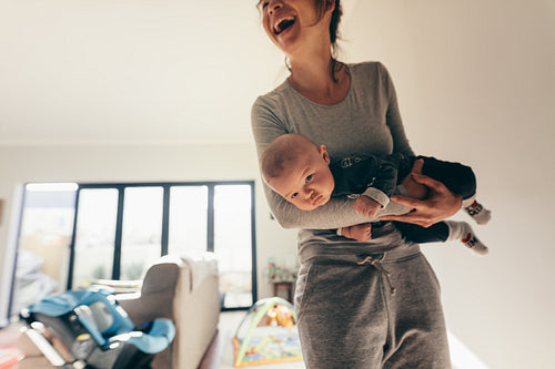 Smiling woman standing in room with her baby