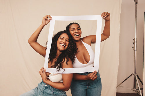 Friends laughing through a picture frame in a studio