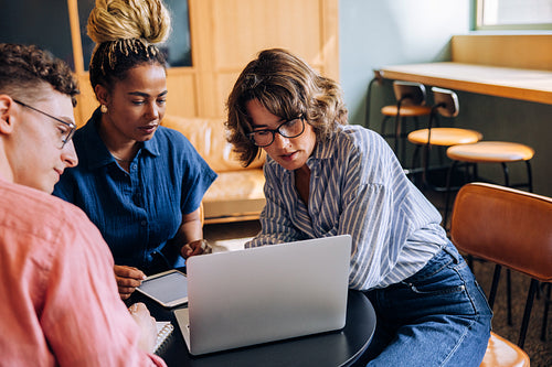 Young professionals collaborating on a project while using a laptop in an office