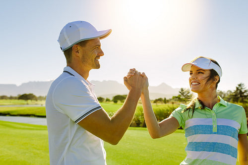 Male and female friends giving high-five at golf course