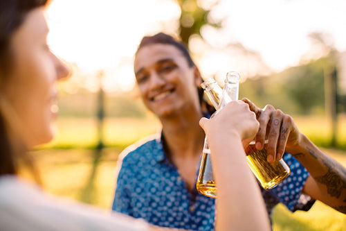 Smiling young couple toasting beer bottles
