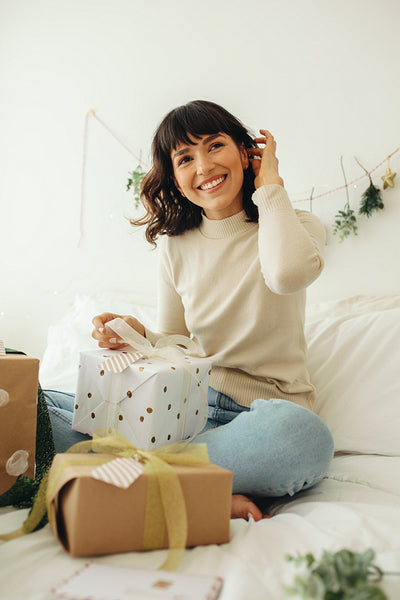 Smiling woman packing christmas gifts