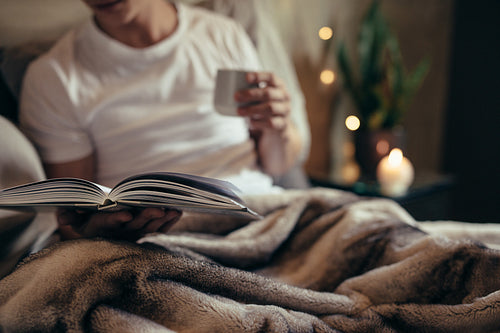 Man reading book on bed at home