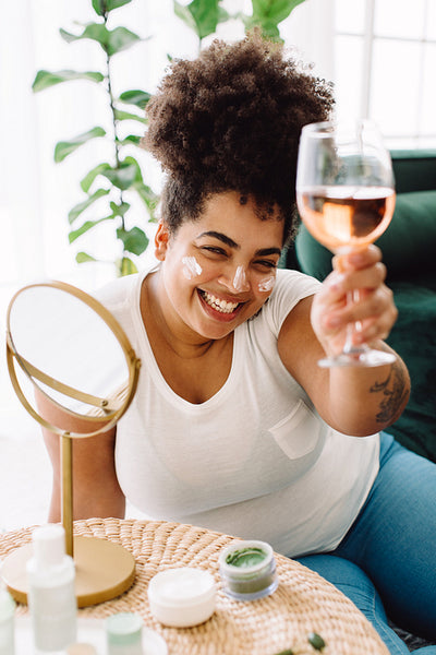 Woman enjoying wine during facial treatment at home