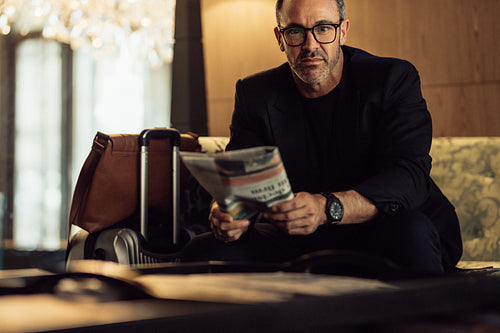 Confident mature businessman sitting in hotel foyer
