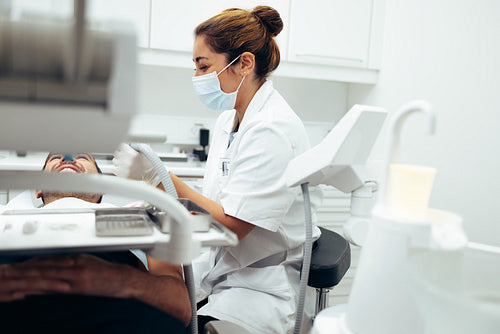 Dentist examining male patient's teeth in clinic