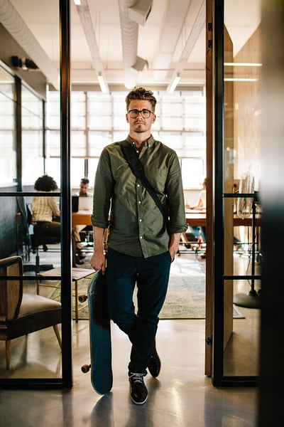 Young man with skateboard in office doorway
