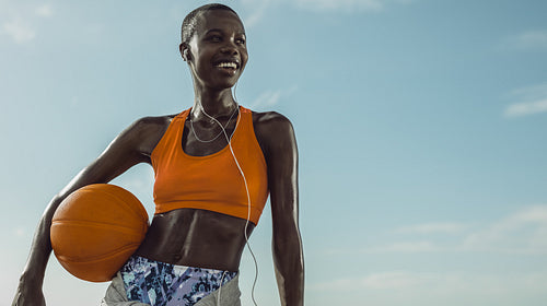 Smiling woman standing outdoors holding a basketball