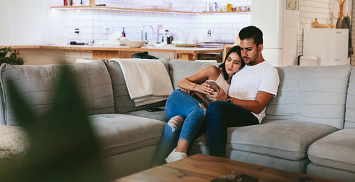 Couple relaxing on couch with smartphone