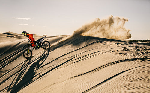 Professional motocross biker riding in sand dunes