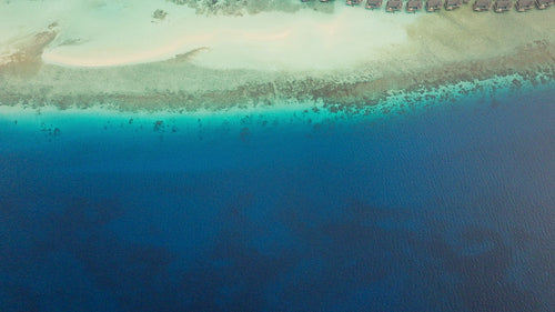 Aerial view of a beautiful tropical island resort with overwater bungalows and crystal clear ocean