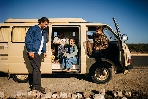 Roadside pause: Friends relax at the open camper door