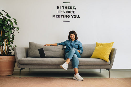 Woman sitting relaxed on sofa in lobby