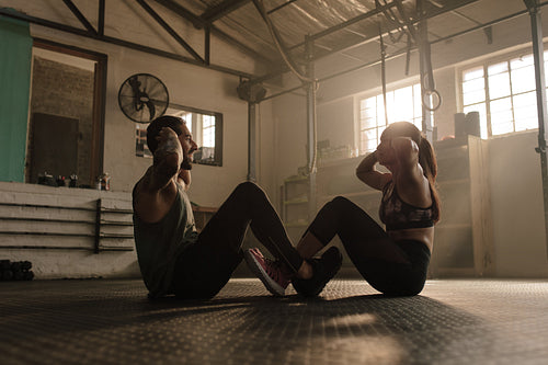 Fitness couple doing abs workout in gym