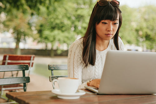 Asian woman working on a laptop at cafe