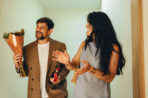 Couple arriving t friends with a bouquet of flowers and a wine bottle