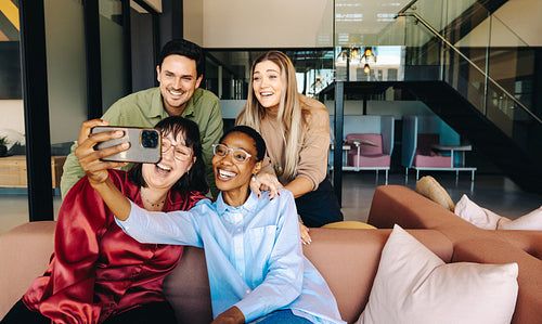 Diverse group of friends taking a selfie in a modern office environment