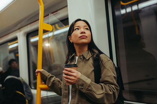 Commuter woman with coffee riding subway and looking up