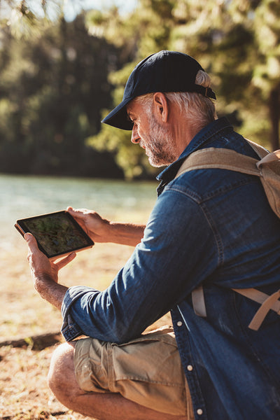 Senior man using digital tab in the forest for navigation