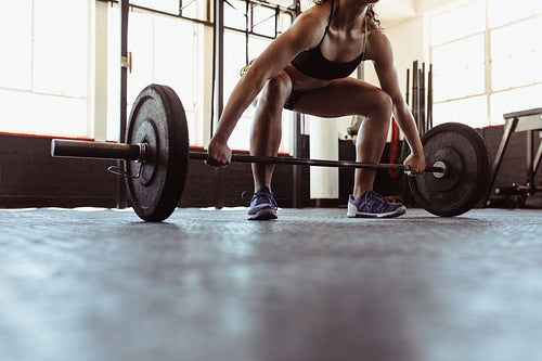 Muscular woman lifting a barbell at the gym