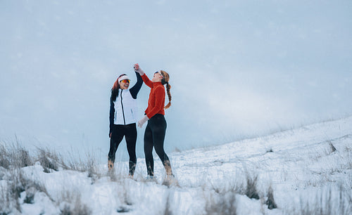 Women celebrate reaching the snow-covered hilltop with high fives